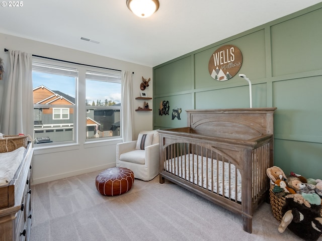 bedroom with a nursery area and light carpet