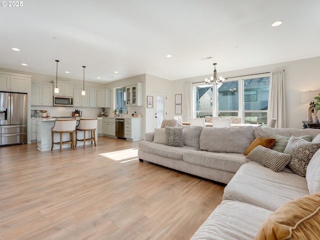 living room featuring a notable chandelier and light wood-type flooring