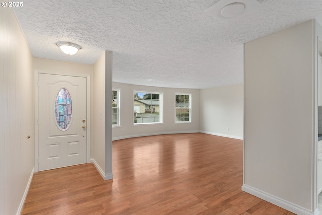 foyer featuring a textured ceiling, baseboards, and light wood-style floors