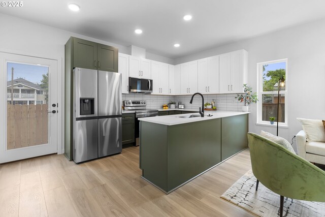 913 NE Sumner St, Portland, OR 97211 - kitchen featuring appliances with stainless steel finishes, a peninsula, healthy amount of natural light, light wood-style flooring, and recessed lighting