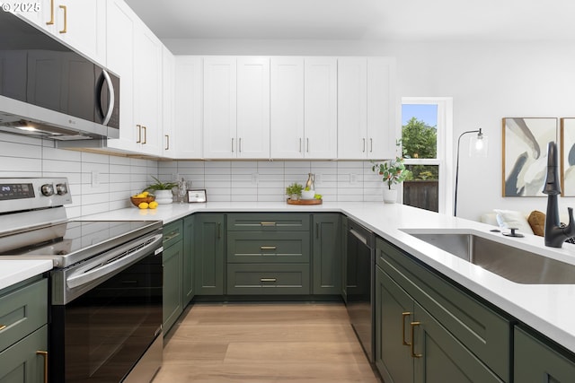 913 NE Sumner St, Portland, OR 97211 - kitchen featuring appliances with stainless steel finishes, green cabinetry, white cabinetry, and tasteful backsplash