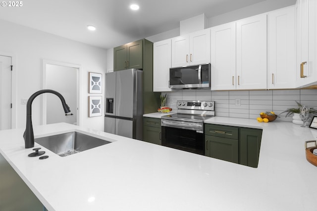 913 NE Sumner St, Portland, OR 97211 - kitchen featuring appliances with stainless steel finishes, green cabinets, decorative backsplash, light countertops, and white cabinets