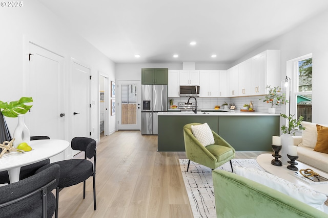 913 NE Sumner St, Portland, OR 97211 - kitchen featuring stainless steel appliances, recessed lighting, light wood-style flooring, tasteful backsplash, and white cabinets