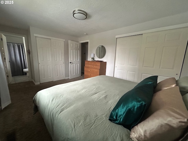 carpeted bedroom featuring multiple closets, a textured ceiling, and ensuite bath