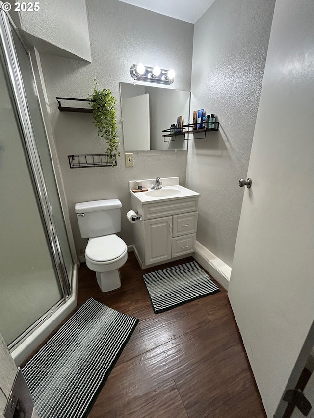 bathroom with vanity, toilet, a shower with door, and hardwood / wood-style floors