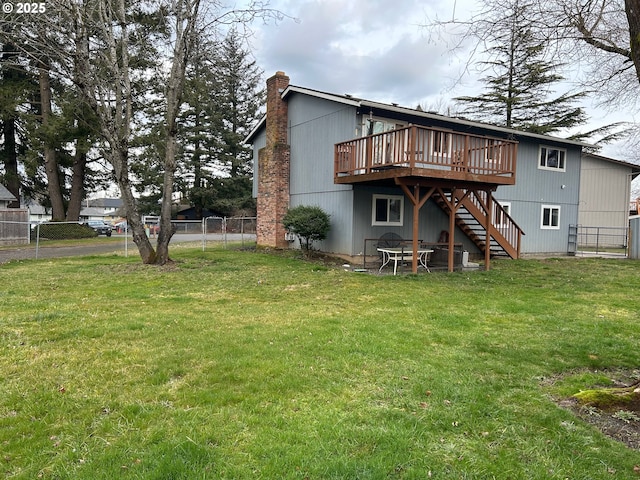 rear view of house with a wooden deck and a lawn