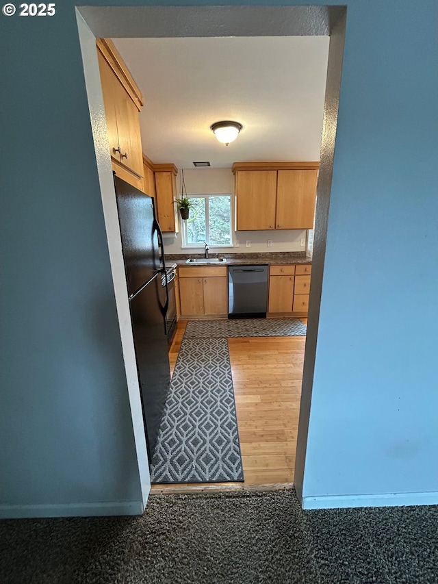 kitchen featuring hardwood / wood-style floors, light brown cabinetry, dishwasher, sink, and black fridge