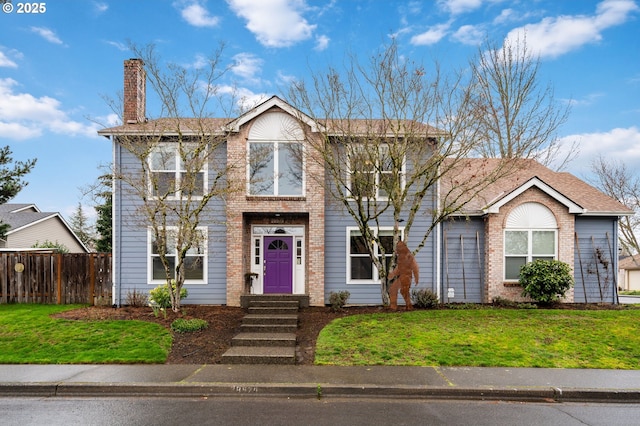 view of front of property with a front yard, fence, brick siding, and a chimney