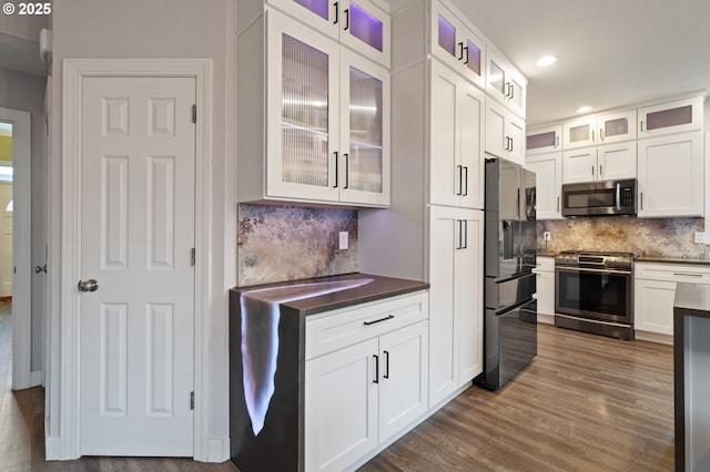 kitchen featuring dark wood finished floors, dark countertops, white cabinets, and appliances with stainless steel finishes