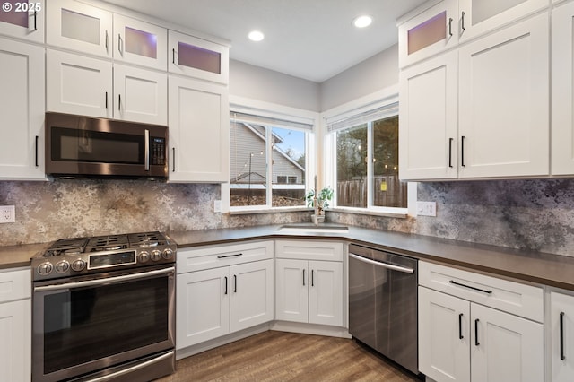 kitchen featuring dark countertops, appliances with stainless steel finishes, white cabinetry, and a sink