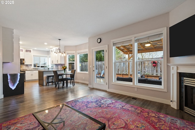 28575 SW Sandalwood Dr, Wilsonville, OR 97070 - living room featuring dark wood-type flooring, a fireplace, baseboards, a chandelier, and recessed lighting