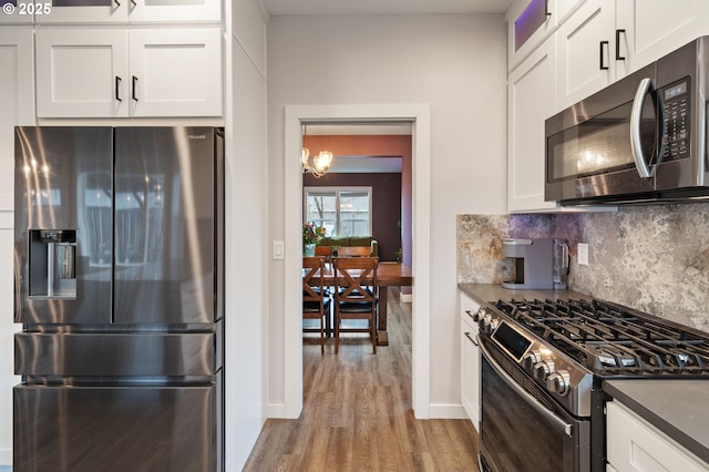 kitchen featuring light wood-style flooring, tasteful backsplash, stainless steel appliances, white cabinets, and glass insert cabinets