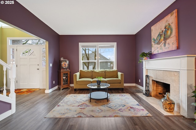 living area featuring a fireplace, stairway, wood finished floors, and baseboards