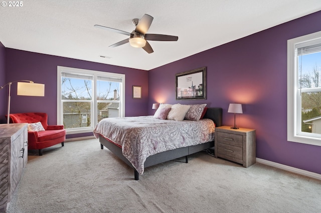 carpeted bedroom with visible vents, multiple windows, baseboards, and ceiling fan