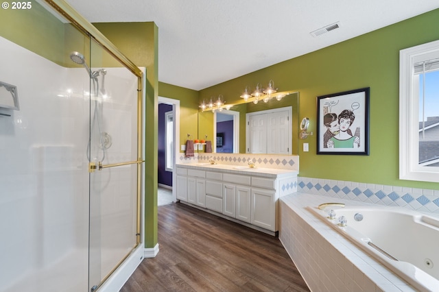 bathroom with visible vents, double vanity, a stall shower, a tub with jets, and a sink