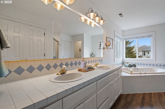 28575 SW Sandalwood Dr, Wilsonville, OR 97070 - bathroom featuring wood finished floors, double vanity, a garden tub, and backsplash