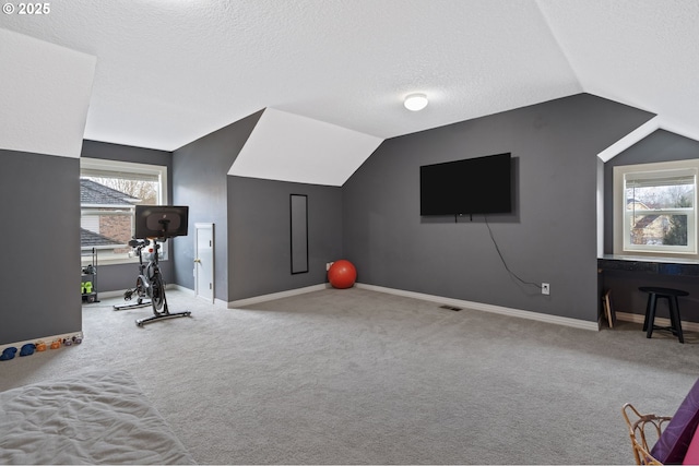 workout area with vaulted ceiling, carpet floors, and a textured ceiling