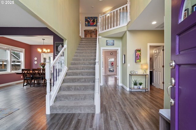 entrance foyer featuring baseboards, dark wood-type flooring, a chandelier, and stairs