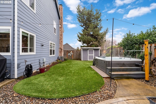 view of yard with a fenced backyard, a storage shed, an outdoor structure, central AC unit, and a hot tub