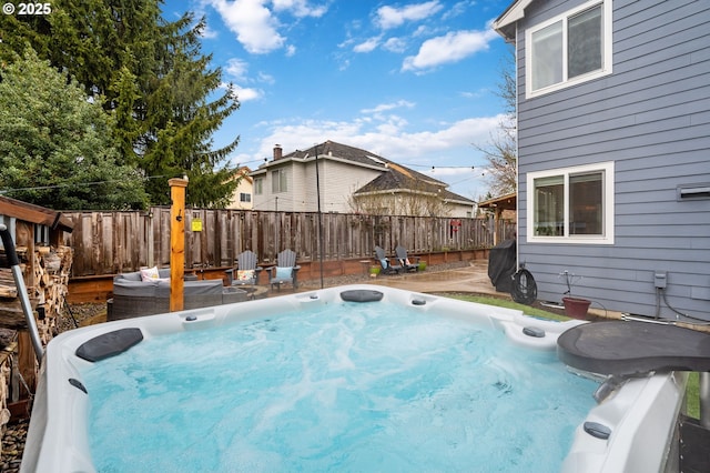 view of swimming pool with fence and a hot tub