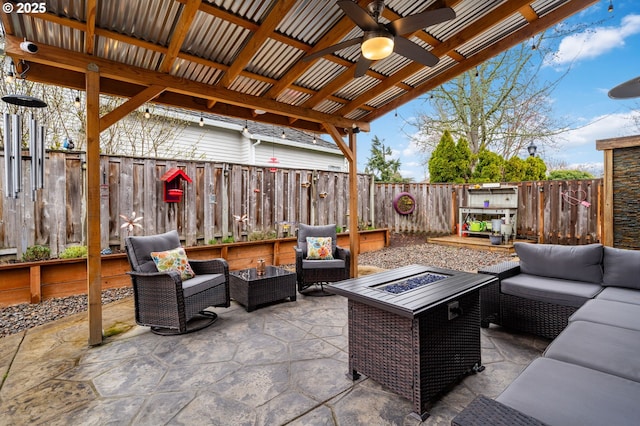 view of patio featuring an outdoor living space with a fire pit, a fenced backyard, and a ceiling fan