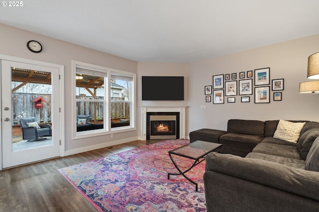 living area with wood finished floors, baseboards, and a warm lit fireplace