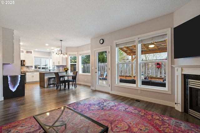 living room featuring visible vents, baseboards, dark wood finished floors, recessed lighting, and a fireplace