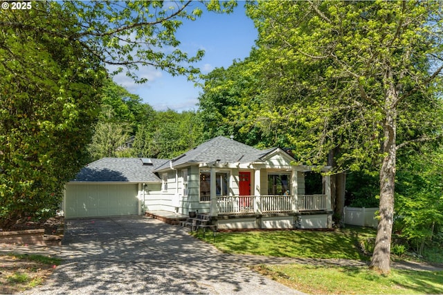 view of front facade with a garage, concrete driveway, a front yard, a porch, and roof with shingles