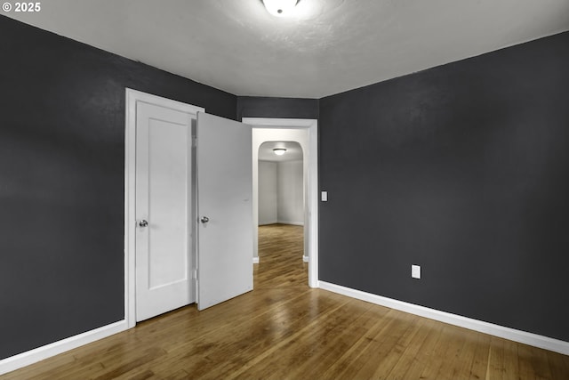 1262 Kalmia St, Junction City, OR 97448 - unfurnished bedroom with arched walkways, baseboards, and wood finished floors