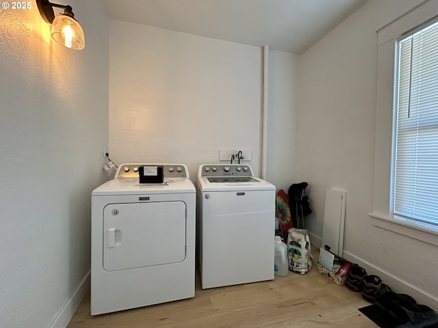 washroom featuring laundry area, light wood finished floors, washer and clothes dryer, and baseboards