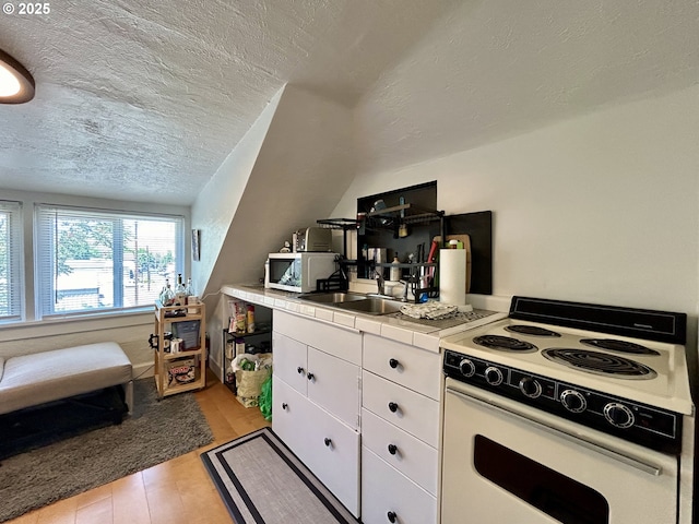 kitchen with white appliances, white cabinets, tile countertops, a textured ceiling, and a sink