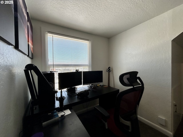 office space featuring a textured ceiling, a textured wall, and baseboards