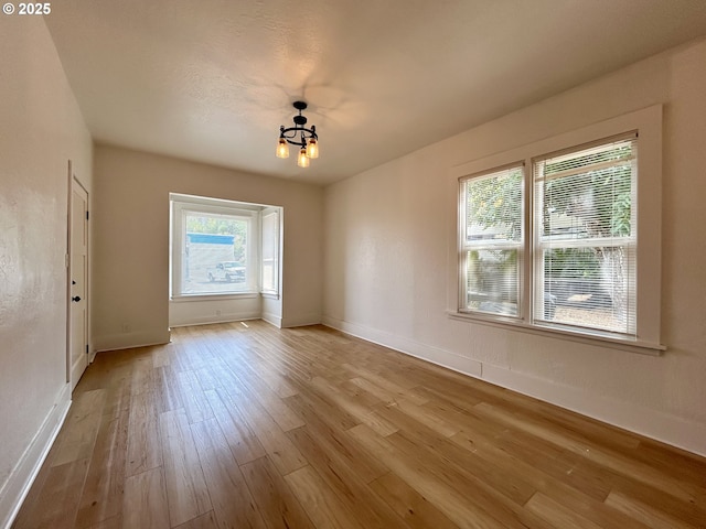 unfurnished dining area featuring an inviting chandelier, baseboards, and wood finished floors