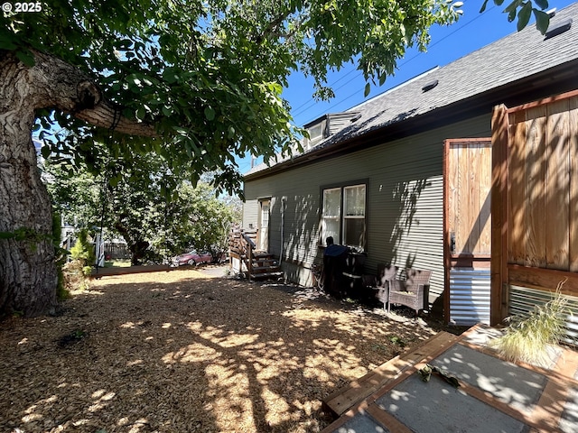 back of property with entry steps and roof with shingles