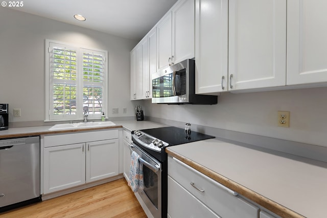 639 1st St, Lake Oswego, OR 97034 - kitchen with stainless steel appliances, a sink, white cabinetry, light countertops, and light wood finished floors