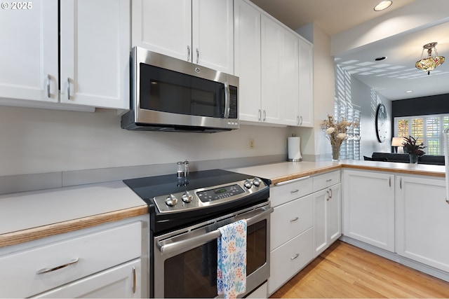 639 1st St, Lake Oswego, OR 97034 - kitchen with stainless steel appliances, white cabinets, light countertops, light wood-type flooring, and recessed lighting