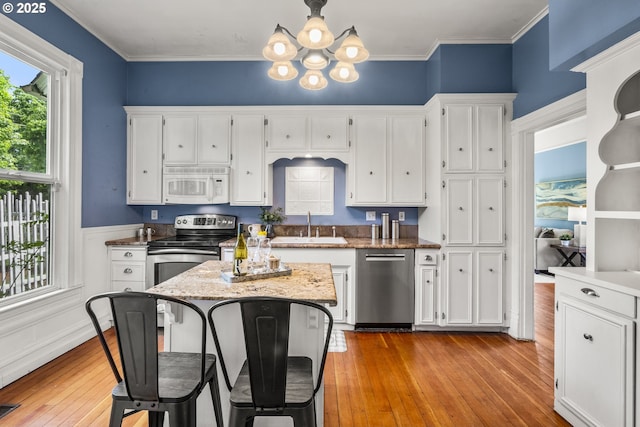 1067 Oak St, Silverton, OR 97381 - kitchen featuring appliances with stainless steel finishes, a sink, a chandelier, white cabinetry, and light wood-style flooring