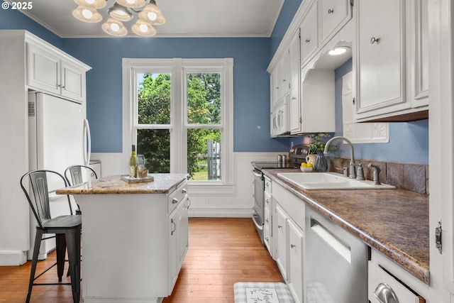 1067 Oak St, Silverton, OR 97381 - kitchen featuring stainless steel appliances, a sink, a kitchen island, a wainscoted wall, and light wood-type flooring