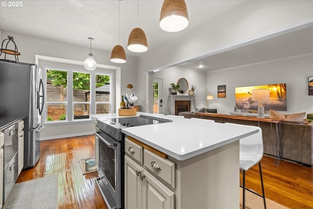 1498 Cathlamet Ct, Salem, OR 97304 - kitchen with appliances with stainless steel finishes, open floor plan, a kitchen island, a fireplace, and dark wood-style floors