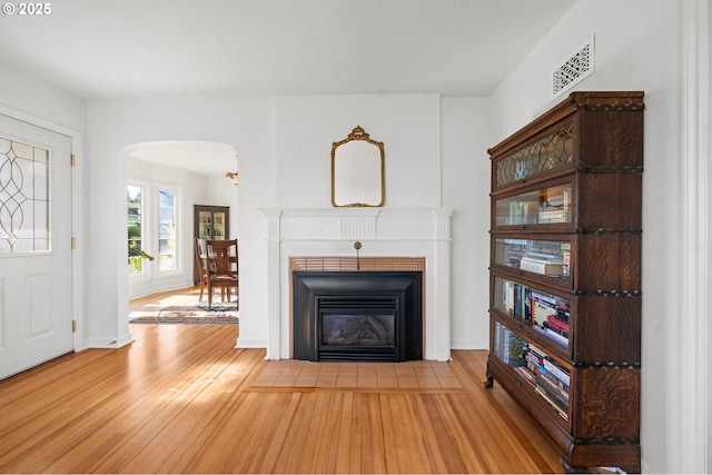 719 6th St, Astoria, OR 97103 - unfurnished living room featuring arched walkways, wood finished floors, and a fireplace with flush hearth