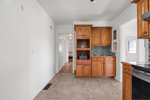 719 6th St, Astoria, OR 97103 - kitchen featuring brown cabinetry, decorative backsplash, light countertops, and stainless steel electric range