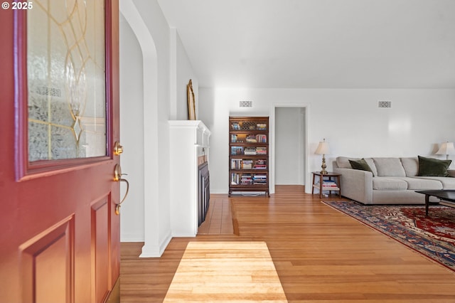 719 6th St, Astoria, OR 97103 - foyer featuring a fireplace, light wood-style flooring, baseboards, and arched walkways