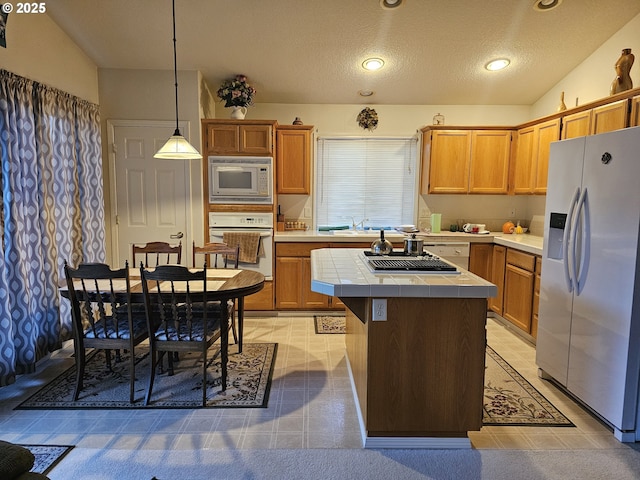 kitchen featuring decorative light fixtures, built in microwave, oven, tile counters, and stainless steel fridge with ice dispenser