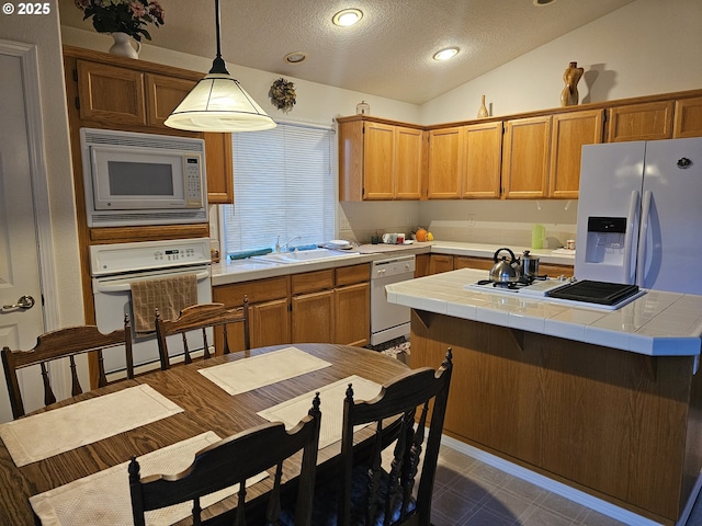 kitchen featuring pendant lighting, lofted ceiling, white appliances, tile counters, and a textured ceiling