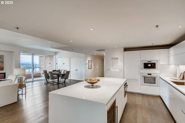 kitchen with modern cabinets, light wood-style floors, open floor plan, white cabinets, and light countertops