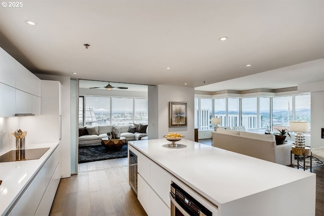 kitchen featuring modern cabinets, black electric cooktop, a kitchen island, white cabinets, and recessed lighting