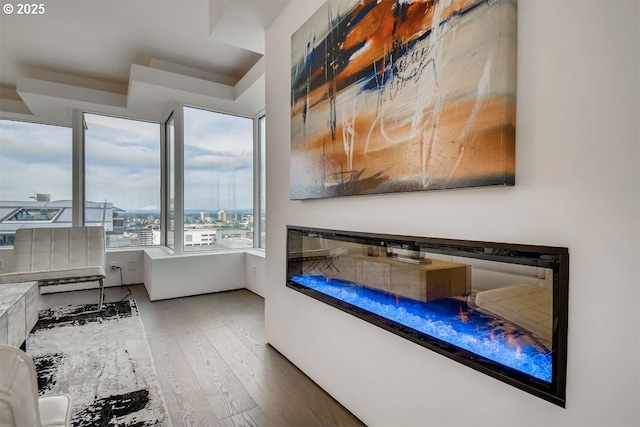 bedroom with wood finished floors and a glass covered fireplace