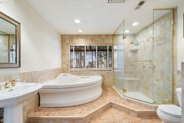 full bathroom featuring a garden tub, tile walls, toilet, a stall shower, and tile patterned floors