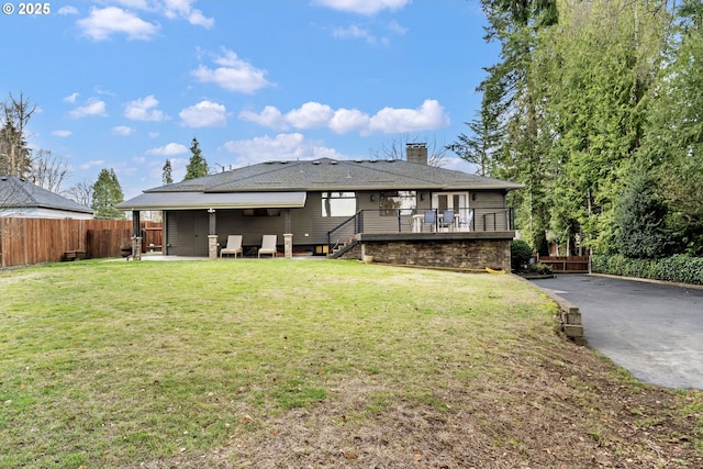 exterior space featuring a chimney, a lawn, a patio area, fence, and stairs