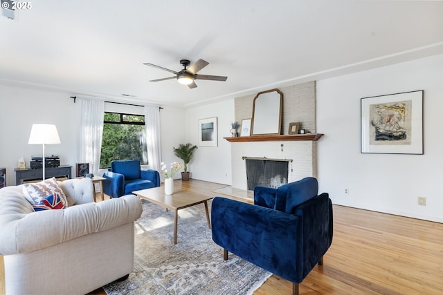 living area featuring a fireplace, wood finished floors, and a ceiling fan